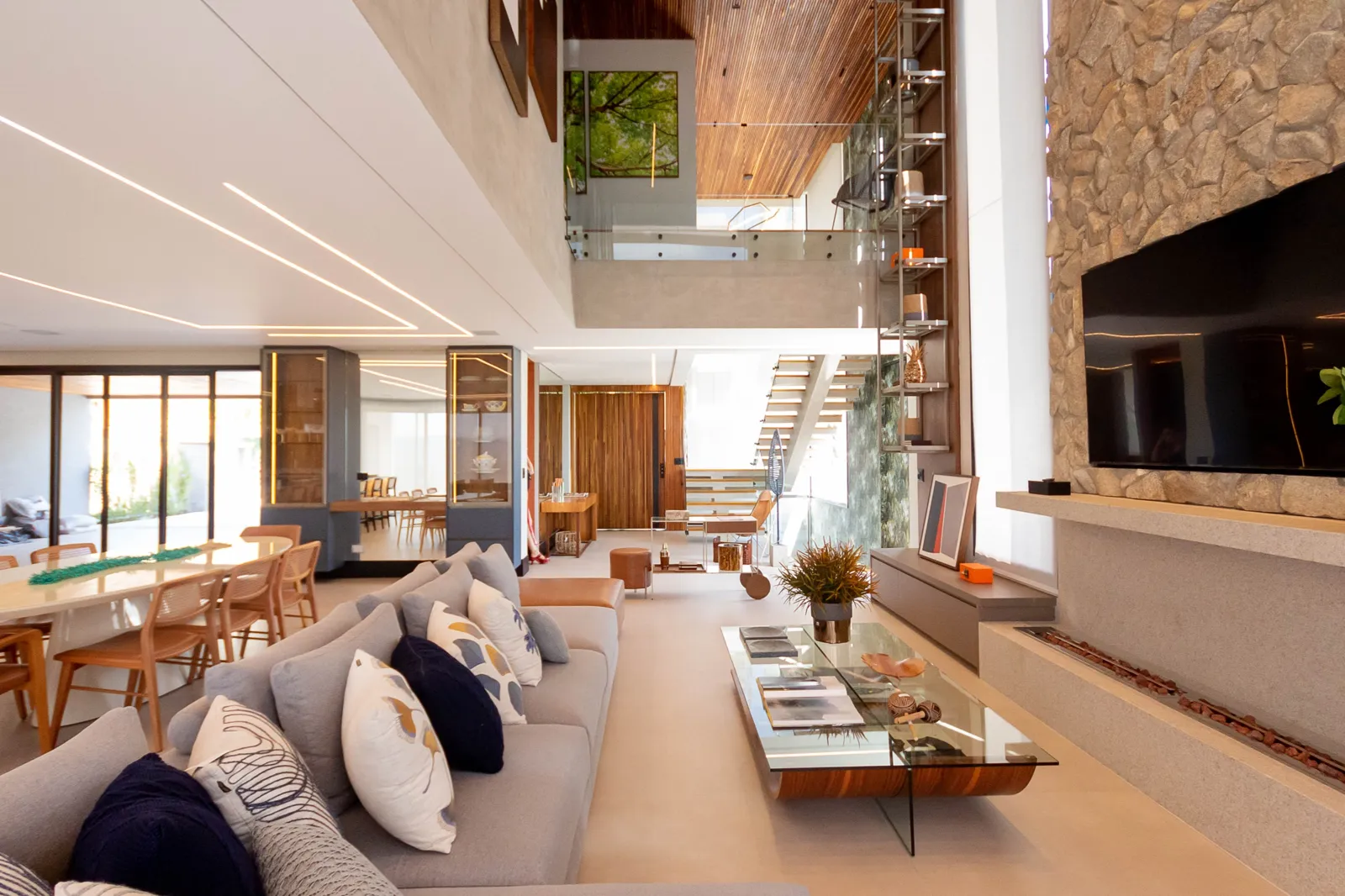Living integrado com pé-direito duplo, lareira e painel de madeira
